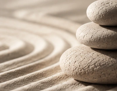 Pale balanced stones and gently raked sand, in neutral limestone tones.